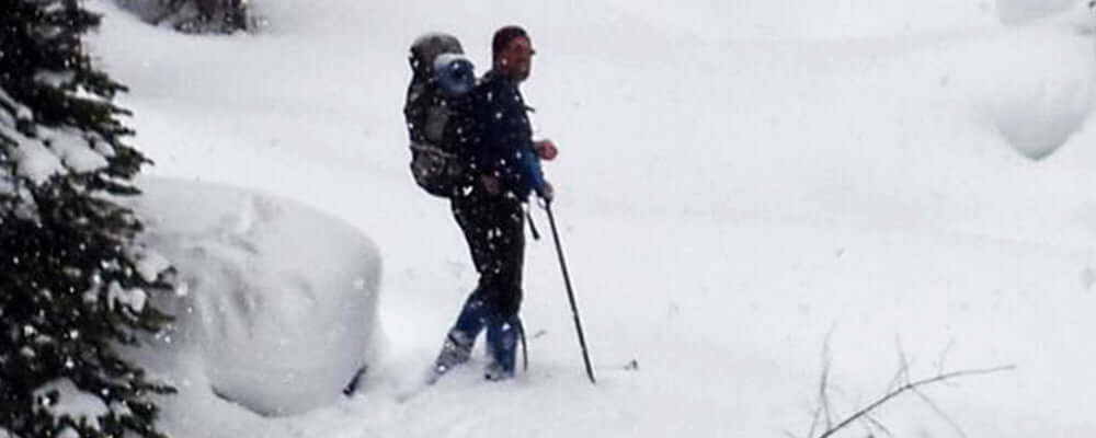 Staff insights - Jeff and backcountry skiing: Jeff hiking through deep snow with a backpack on.