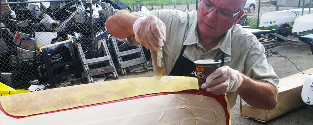 Person applying skid plates to a canoe, demonstrating how to apply skid plates for protection.