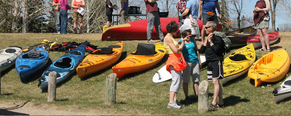 How to Choose Your First Kayak: a Beginner's Guide - Colorful kayaks and people enjoying a paddling event.