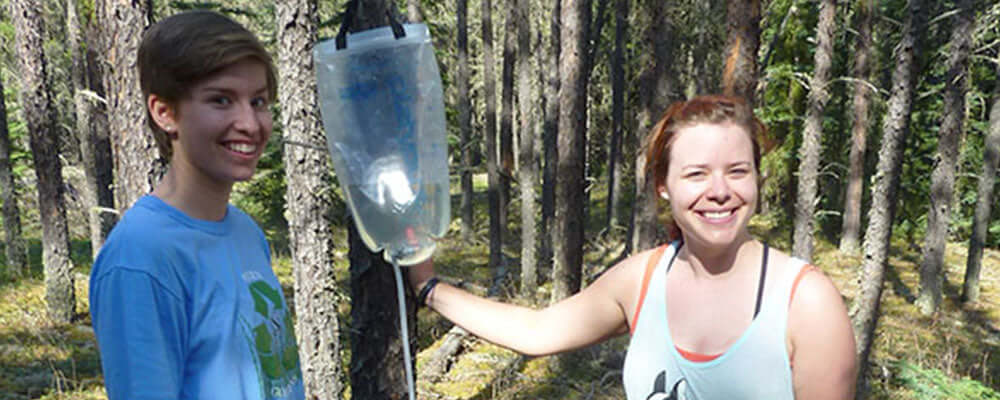 Product review: Platypus Gravity Works being tested in the forest by two users with a water filter.