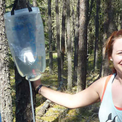 Product review: Platypus Gravity Works being tested in the forest by two users with a water filter.