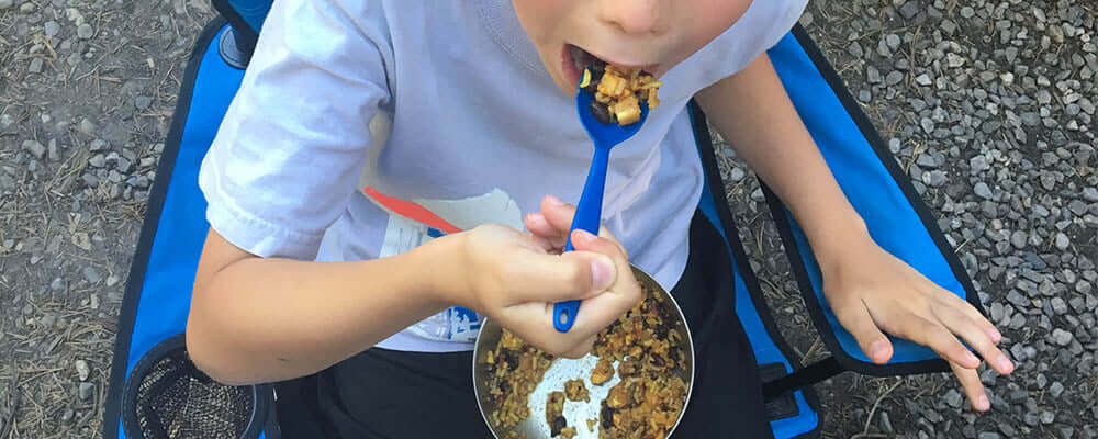 Child enjoying a meal while sitting outdoors, emphasizing the joys of dehydrated vs freeze-dried foods | which is better?