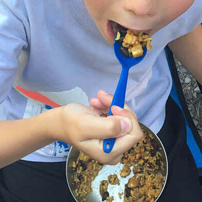 Child enjoying a meal while sitting outdoors, emphasizing the joys of dehydrated vs freeze-dried foods | which is better?