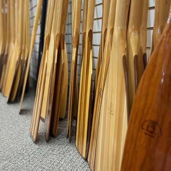 Wood canoe paddles lined up against a wall