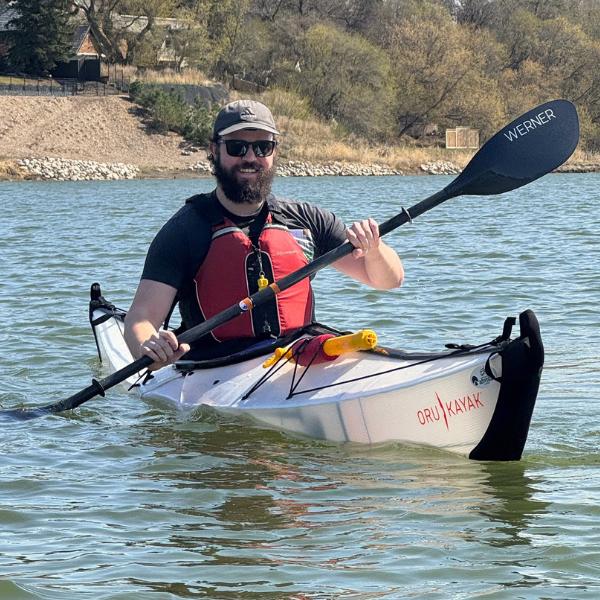 Man paddling a small white kayak