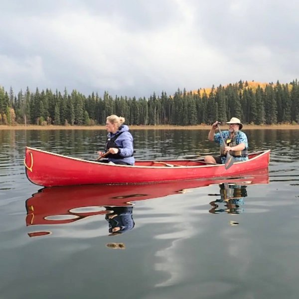Two people paddling a red canoe on a lake