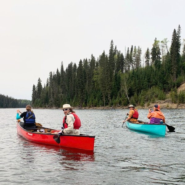 People paddling 2 canoes on a lake
