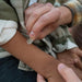 Close-up of two people holding hands, with one person wearing a plaid shirt.