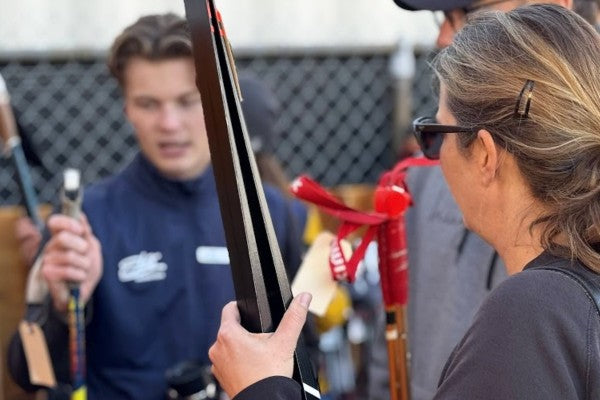 Person holding a pair of nordic skis with another person in the background