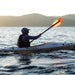 Person kayaking on a body of water with mountains in the background