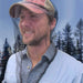 Man wearing a cap with a net over his head in a forest setting
