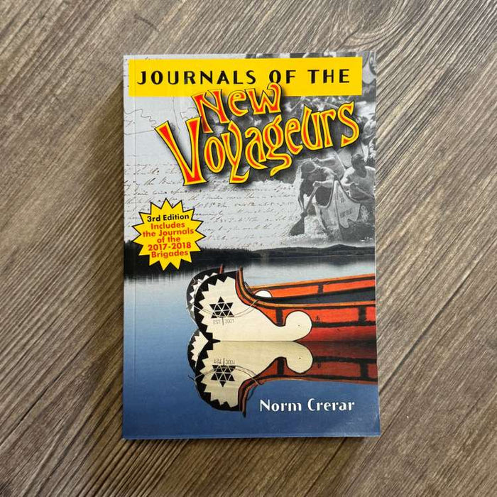 Book titled 'Journals of the New Voyageurs' by Norm Crerar on a wooden surface
