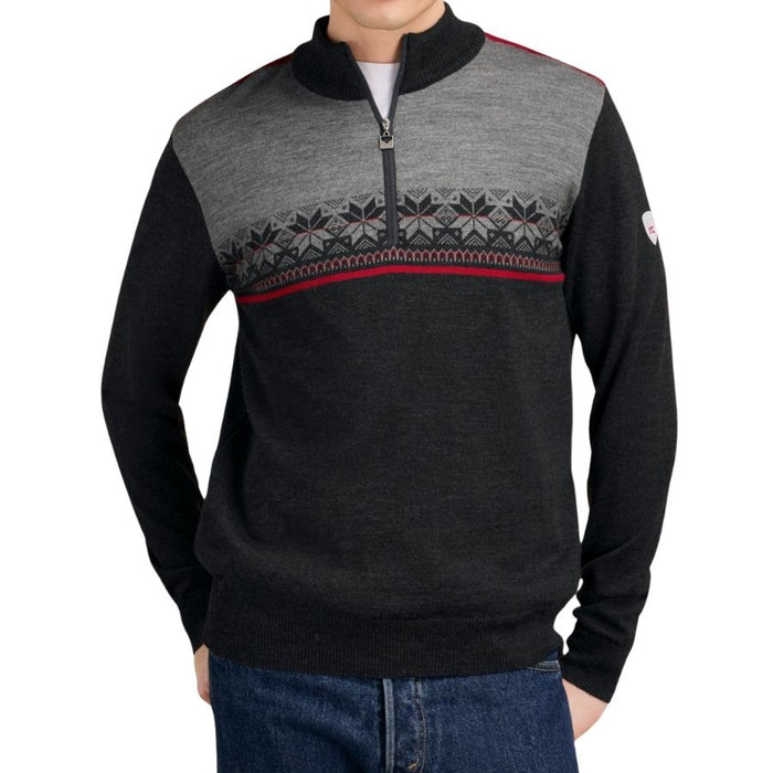 A man wearing a dark charcoal and gray quarter-zip sweater with a Nordic pattern across the chest and blue jeans, shown from the neck down on a white background.