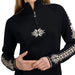 A close-up of a person wearing a black quarter-zip pullover sweater with white Fair Isle snowflake and geometric patterns on the chest and sleeves, set against a plain white background.