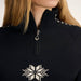 Close-up of a person wearing a black quarter-zip knit top with a white snowflake motif on the chest and white geometric accents near the shoulders.