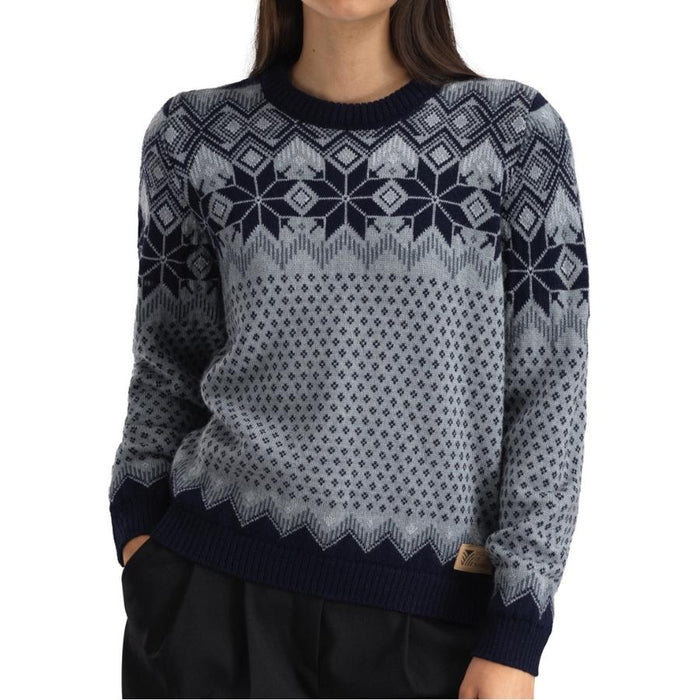 Woman wearing a grey sweater with a navy nordic pattern against a white background.
