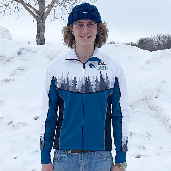 Person wearing a blue and white jacket with a forest design, standing in a snowy landscape.