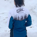 Person wearing a blue and white jacket with 'Eb's Saskatoon' branding in the snow.