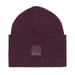 A dark plum purple ribbed knit beanie hat with a square embossed logo patch on the front cuff, shown against a plain white background.