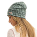 A woman in profile wearing a slouchy knit beanie with a green and gray Nordic snowflake pattern and a small pink embroidered logo.