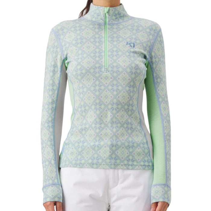 A woman wearing a long-sleeve quarter-zip athletic top with a light blue and mint green geometric diamond pattern, paired with white pants, against a plain white background.