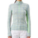 A woman wearing a long-sleeve quarter-zip athletic top with a light blue and mint green geometric diamond pattern, paired with white pants, against a plain white background.