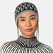 A woman wearing a black and white knit beanie with a snowflake pattern and a matching black and white striped turtleneck sweater, shown against a light gray background.