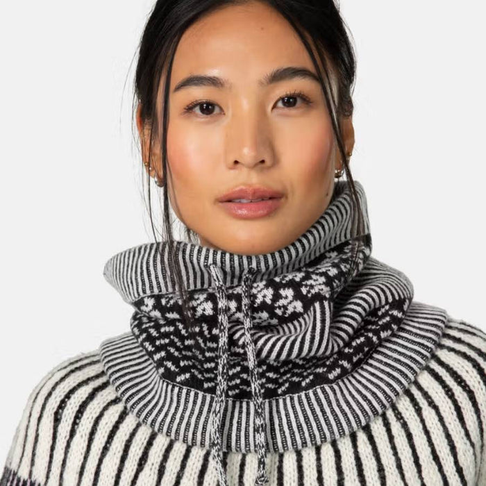 Woman wearing a black and white patterned sweater and neck tube against a white background.