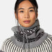 Woman wearing a black and white patterned sweater and neck tube against a white background.