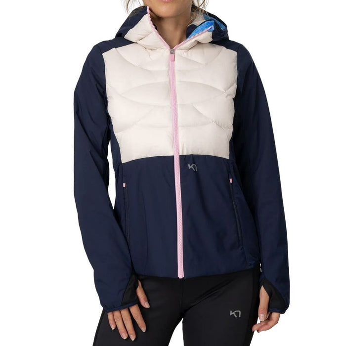 A woman wearing a colorblock hooded jacket with a navy blue lower half, a cream quilted upper panel, and a light pink front zipper. The jacket features a small white KT logo on the chest.