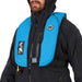 Person in black jacket wearing a blue PFD against a white background