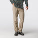A person wearing tan cargo-style pants with a green plaid shirt and dark shoes, photographed against a clean light gray studio background.