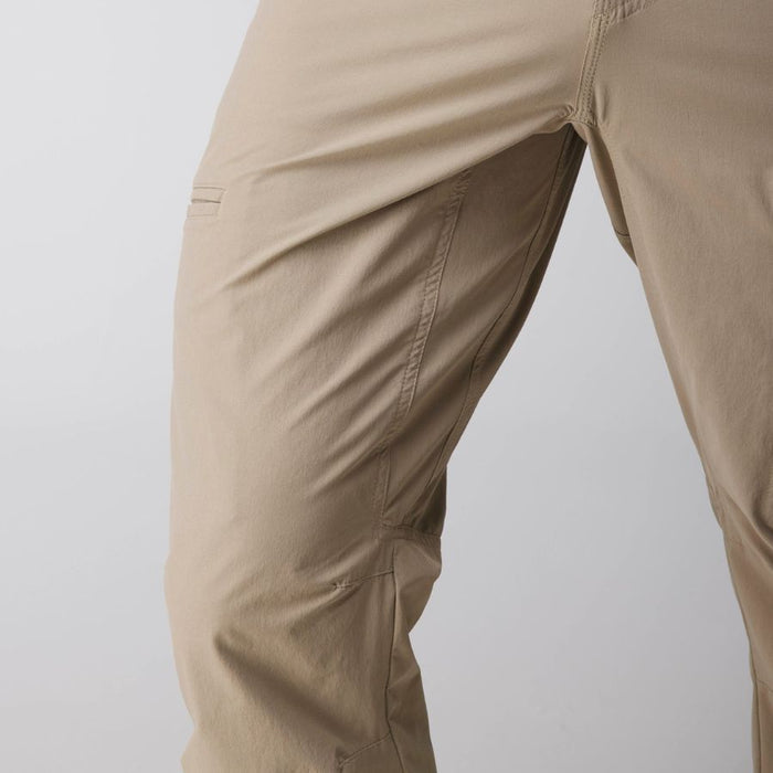 Close-up of khaki-colored outdoor pants showing the thigh, pocket, and fabric texture against a light gray background.