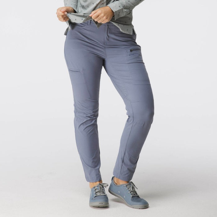 A model wearing slate blue slim-fit hiking pants, a matching gray patterned long-sleeve shirt, and gray trail shoes, shown from the waist down against a light gray studio background.