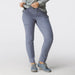 A model wearing slate blue slim-fit hiking pants, a matching gray patterned long-sleeve shirt, and gray trail shoes, shown from the waist down against a light gray studio background.