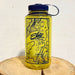 Yellow water bottle with navy blue lid and map design on a wooden surface