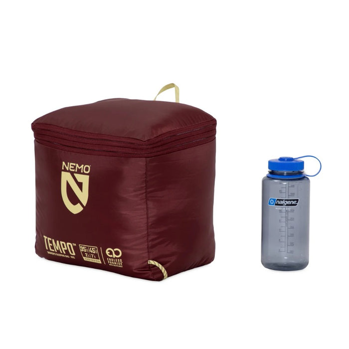 Maroon sleeping bag with Nemo logo and a gray water bottle with blue cap on a white background
