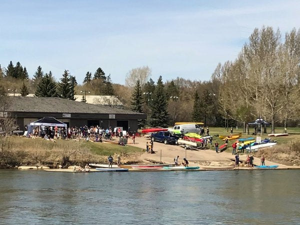 Group of people by a lake with boats and a building in the background