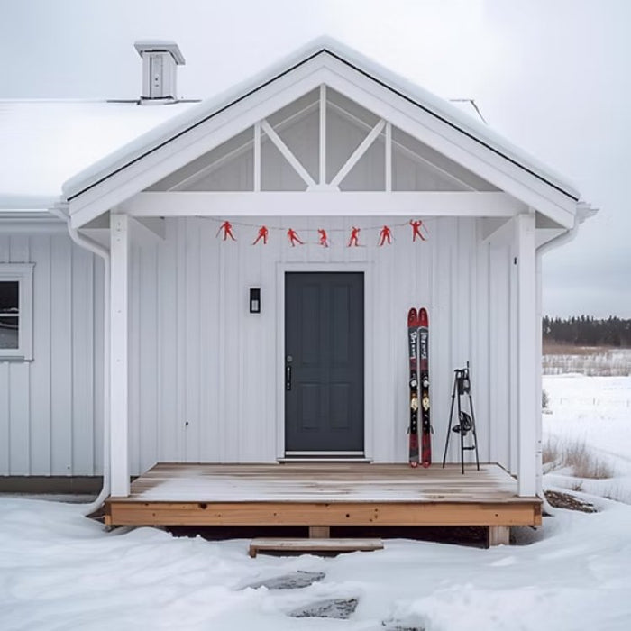 White cabin with a wooden deck in a snowy landscape