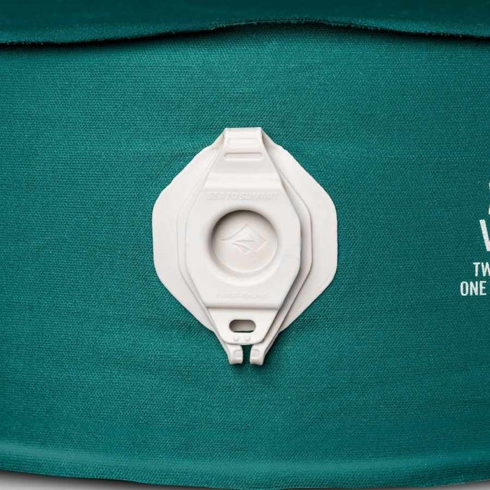 Close-up of a white plastic valve fitting attached to a teal fabric surface with partial white printed text visible on the right.