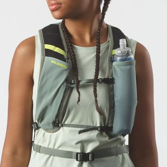 Woman wearing a light green top and running vest with flask