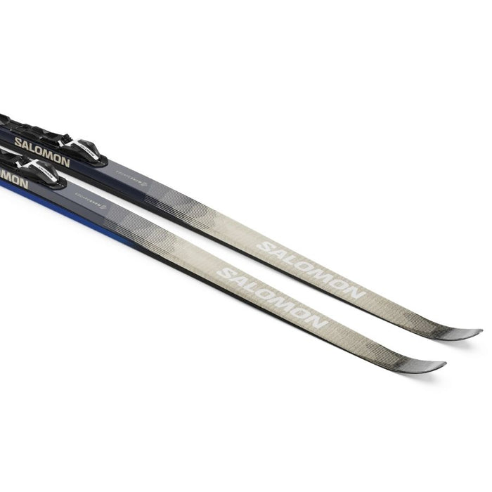 Close up of the front of a pair of beige and grey skis with Salomon branding against a white background.