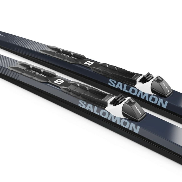 Close up of black and white bindings mounted on dark blue skis with Salomon branding against a white background.