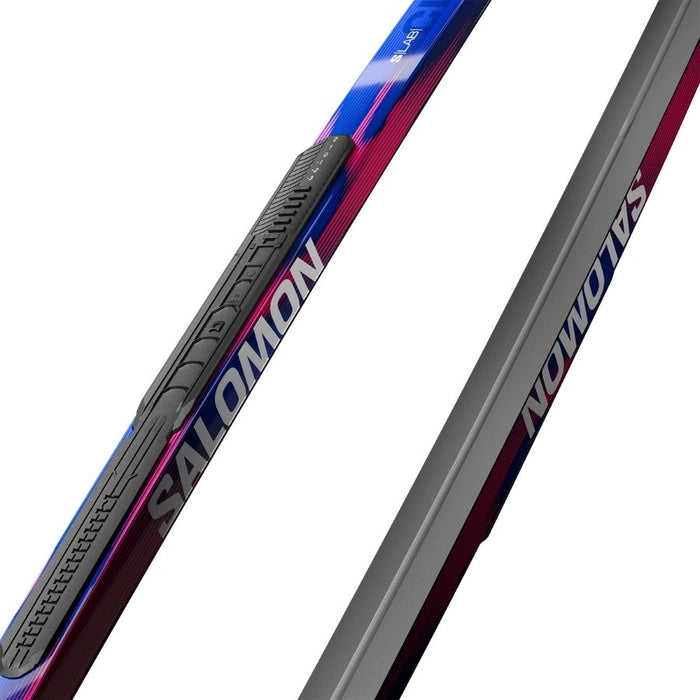 Close up of blue and pink skis with Salomon branding against a white background.