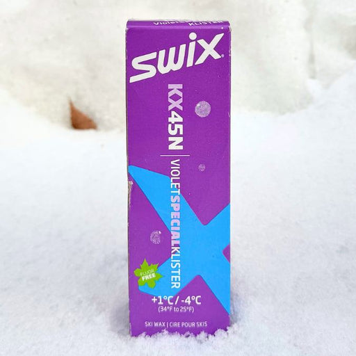Swix box of violet klister against a snowy background