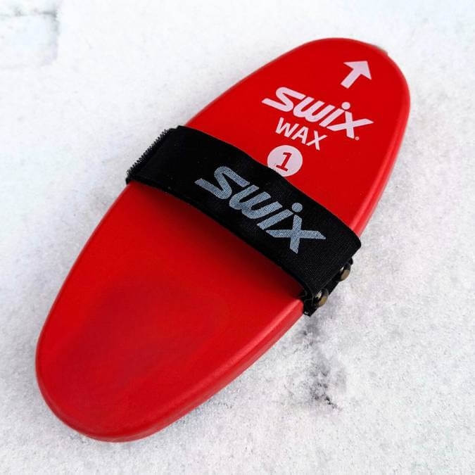 Red swix ski wax tool on a snowy background
