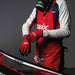 Person wearing a red Swix apron and gloves, standing next to a ski with a gray background.
