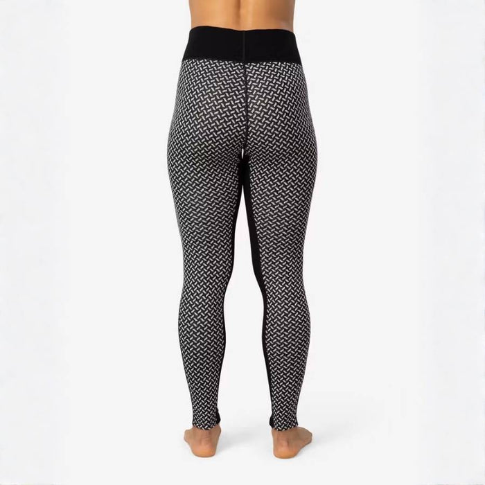 Rear view of a person wearing high-waisted black and white patterned leggings against a plain white studio background.