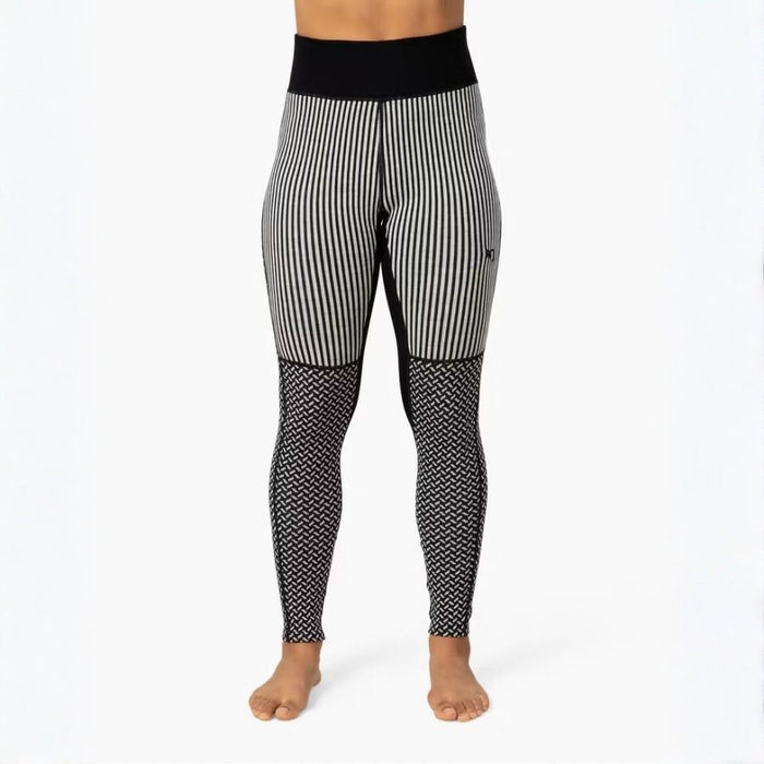 Black and white patterned leggings worn by a model, featuring vertical stripes on the upper legs and a black-and-white geometric pattern on the lower legs, shown against a plain white background.