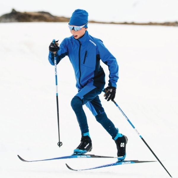 Boy wearing blue clothing skiing on a snowy landscape.